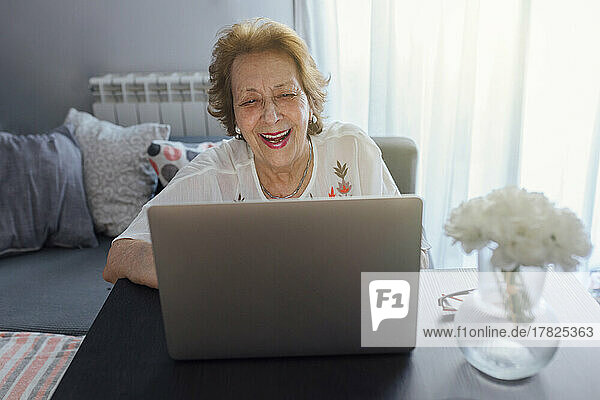 Happy senior woman using laptop at home