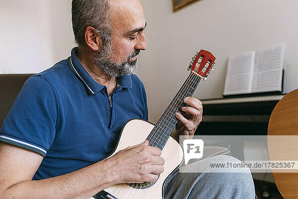 Mature man playing ukulele at home