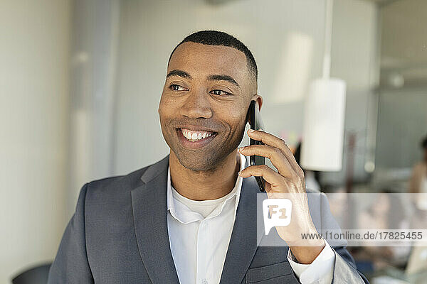 Happy businessman talking on mobile phone at office