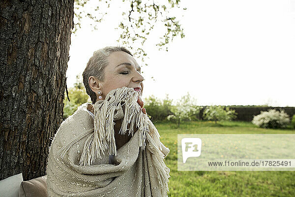 Woman with eyes closed wrapped in blanket