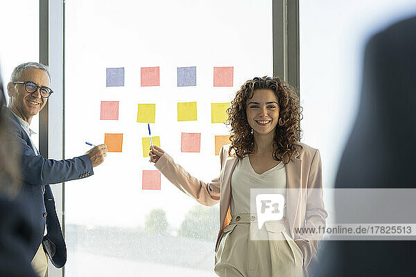 Business colleagues explaining strategy through adhesive notes in meeting at office