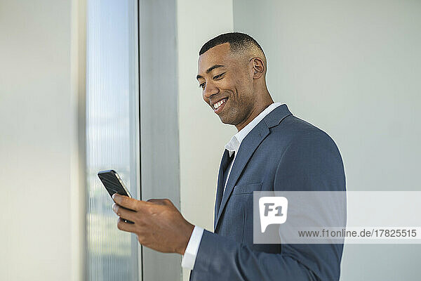 Smiling businessman using smart phone at office