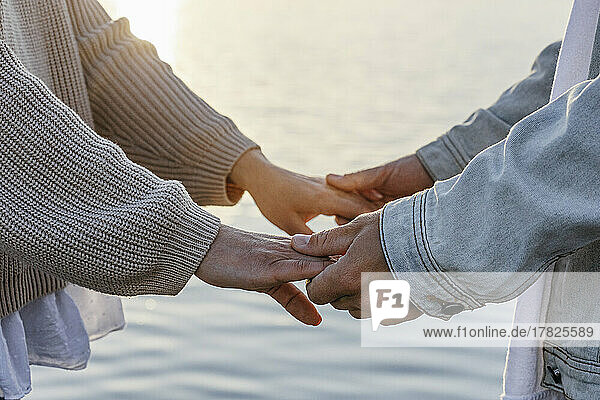 Mann hält die Hände seiner Freundin am Strand