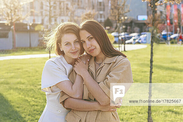 Happy woman with friend standing at park on sunny day