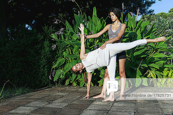 Yogalehrerin mit Teenager-Mädchen beim Stretching im Park