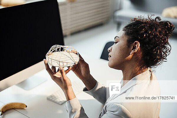 Businesswoman examining architectural model at office