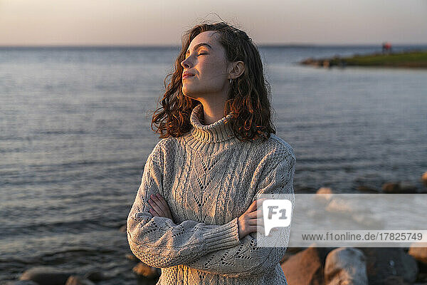 Smiling young woman with eyes closed enjoying sunset