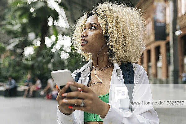 Young woman looking away holding smart phone