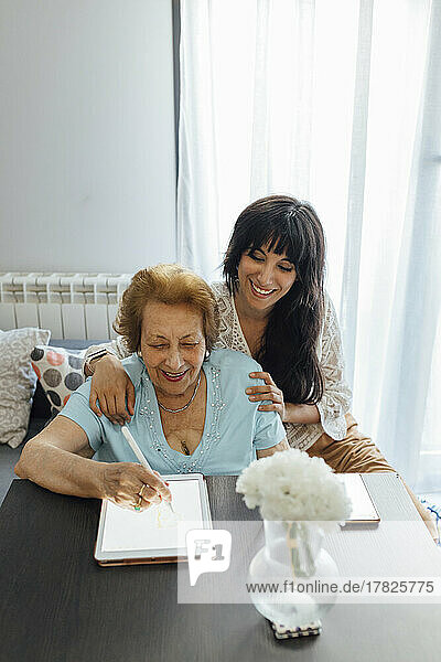 Happy woman with grandmother using tablet PC at home