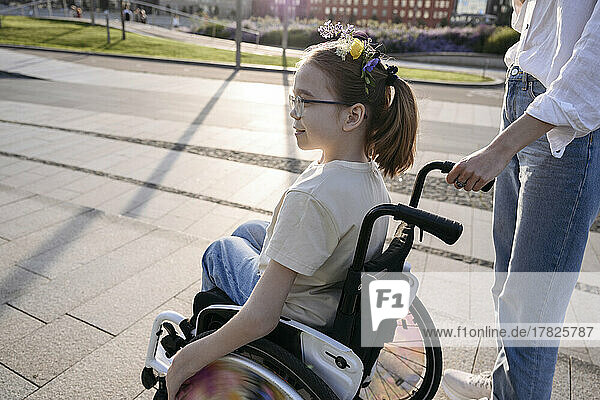 Woman with girl in wheelchair at park on sunny day