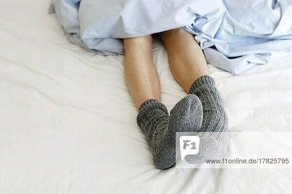 Frau mit kuscheligen Socken auf dem Bett
