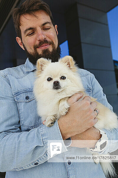 Glücklicher Mann steht mit Pomeranian-Hund