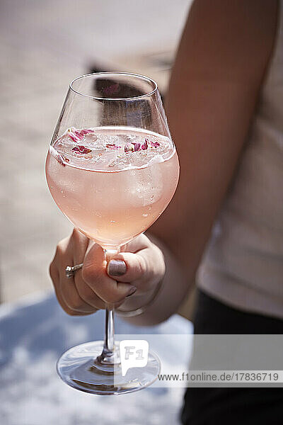 Hand holding stemmed glass with summer berry drink