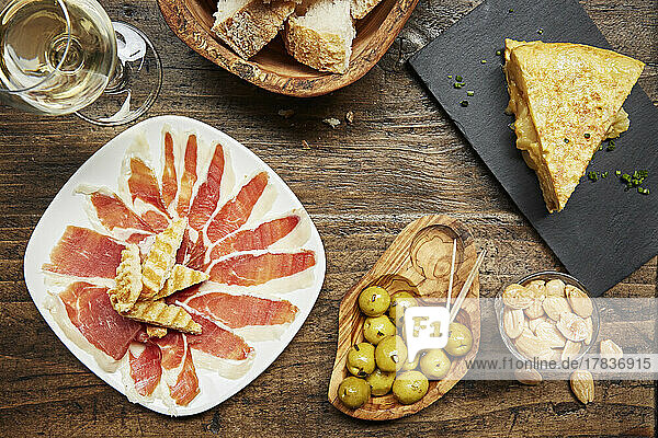 Spanische Tapas: Schinken  Oliven und Tortilla mit Mandeln und Brot auf Holztisch