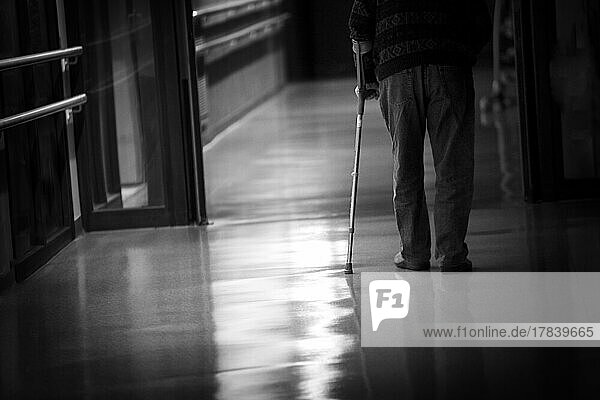 Man with a cane walking in a hallway of a retirement home.