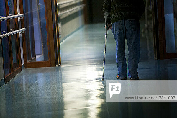 Elderly man with his cane in a hallway of a retirement home.