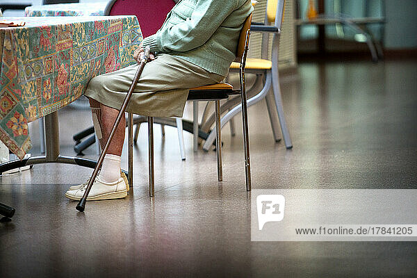 Elderly woman with her cane in a retirement home.