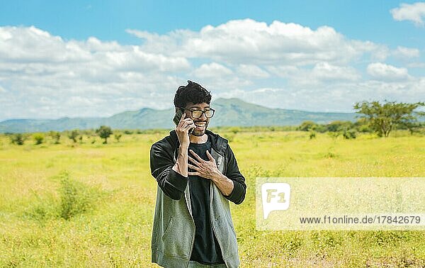 Smiling man calling on the phone on the field  people talking on the cell phone in the field. Man calling on the phone in the field  A man in a beautiful field talking on the phone