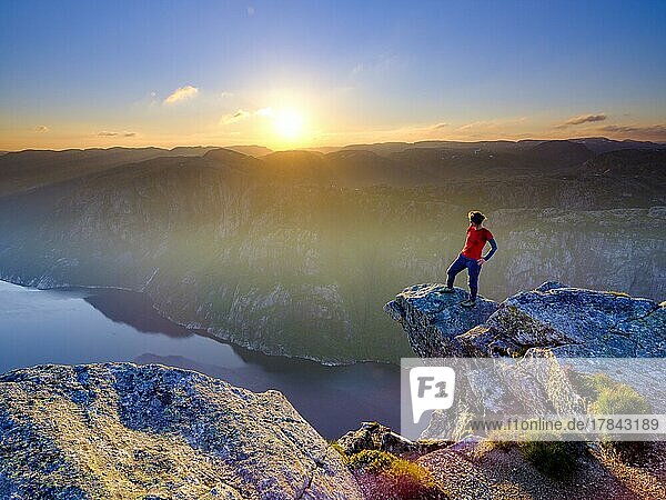 Woman standing on a rocky outcrop at Kjerag above the Lysefjord  sunset  Lyseboten  Rogaland  Norway  Europe