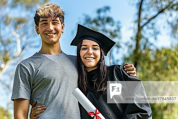 Glückliches kaukasisches Mädchen mit ihrem Freund oder ihrem Bruder am Tag ihres Abschlusses