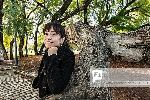Eine Frau posiert mit Blick in die Kamera in einem öffentlichen Park