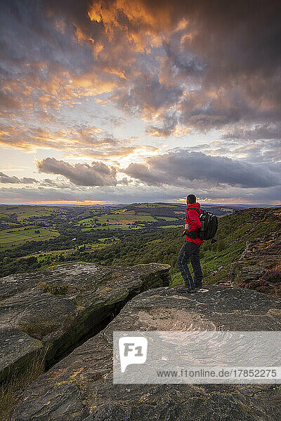 Ein Wanderer steht bei Sonnenuntergang auf Curbar Edge  Derbyshire  Peak District  Derbyshire  England  Vereinigtes Königreich  Europa