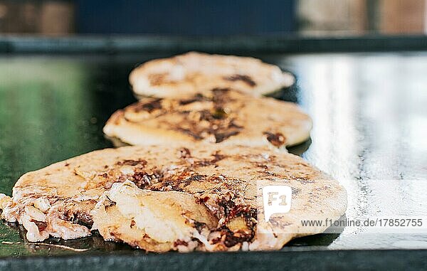 Traditional Nicaraguan pupusas with melted grilled cheese  Traditional cheese pupusas on the grill  Close up of traditional handmade pupusas on the grill