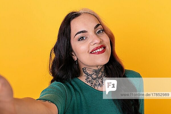 Porträt einer attraktiven Frau  die ein Selfie auf gelbem Hintergrund macht