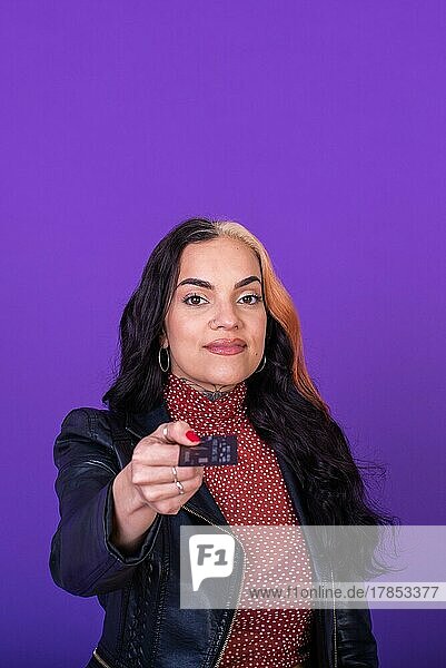 Frau zeigt eine Kreditkarte auf lila Hintergrund. Shopping-Konzept. Kopieren Raum