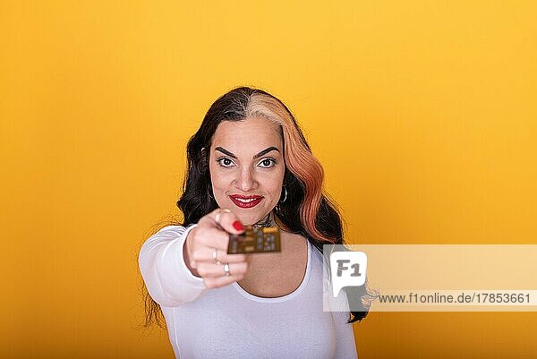 Frau zeigt eine Kreditkarte auf gelbem Hintergrund