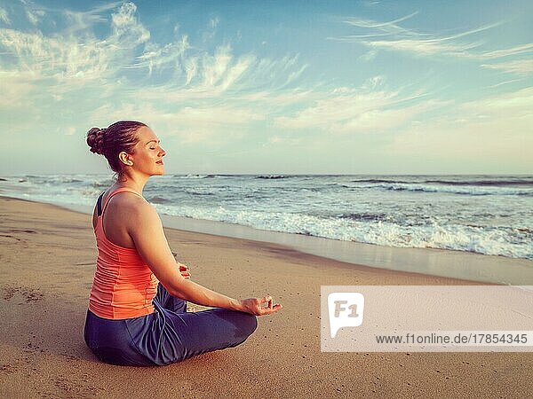 Vintage Retro-Hipster-Effekt Bild der Frau tun Yoga meditieren und entspannen in Padmasana Lotus Pose mit Kinn Mudra im Freien am tropischen Strand bei Sonnenuntergang