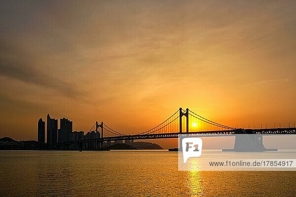 Gwangan-Brücke bei Sonnenaufgang mit Wolkenkratzern und dramatischem Himmel. Busan  Südkorea  Asien