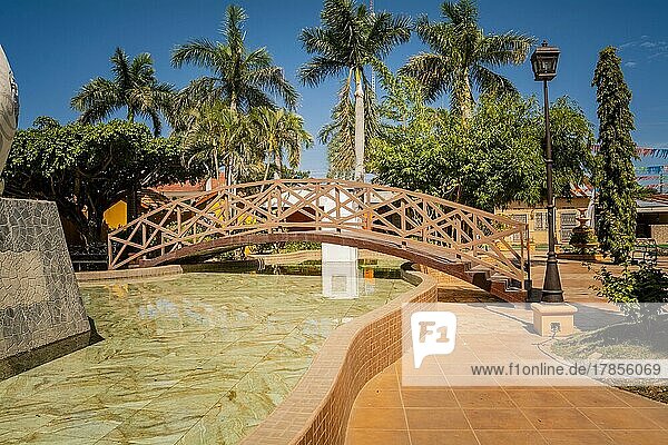 Seitenansicht einer kleinen Holzbrücke über einen Wasserbrunnen in einem ruhigen Park. Nagarote Zentralpark. Blick auf einen schönen und entspannten Park mit einem Wasserbrunnen. Traditioneller Park von Nagarote  Nicaragua  Mittelamerika