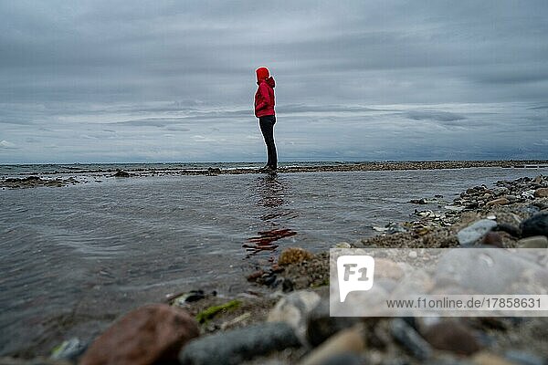 Frau in Rot steht am Strand an der Ostsee  Rügen  Deutschland  Europa