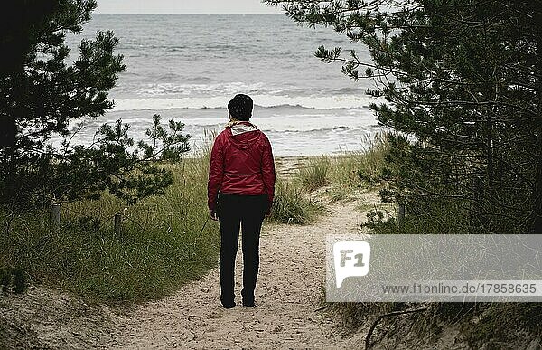 Woman in red standing on the sandy beach on the Baltic Sea  Rügen Island  Germany  Europe