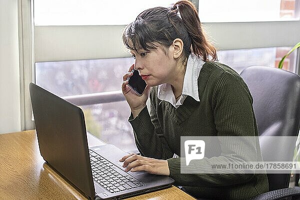 Porträt einer Frau  die im Büro an ihrem Laptop arbeitet