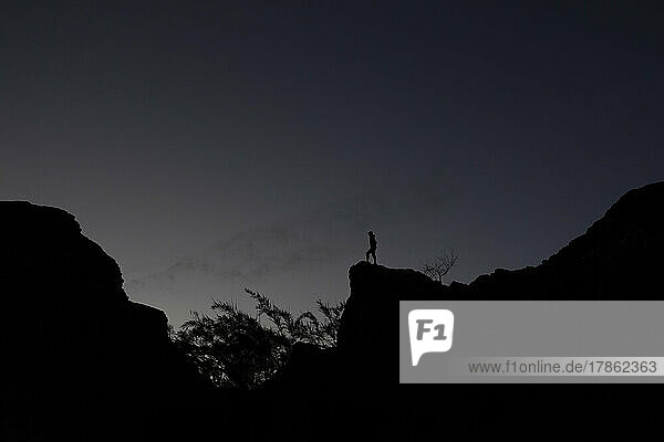 The lonely figure of a woman on a rock buttress at sunset