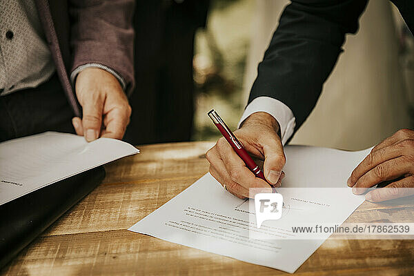 Groom's hand signing the registry at a civil wedding
