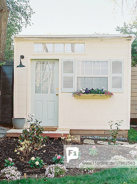 Tiny shed with blue door  shutters  and garden