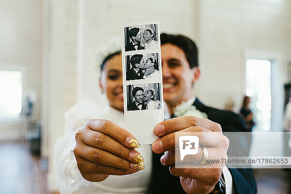 Bride and groom smile holding polaroid photograph of them