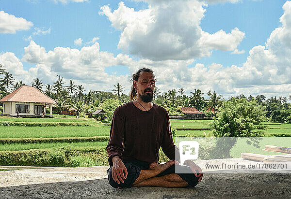 A man meditates in the lotus position on the background of rice