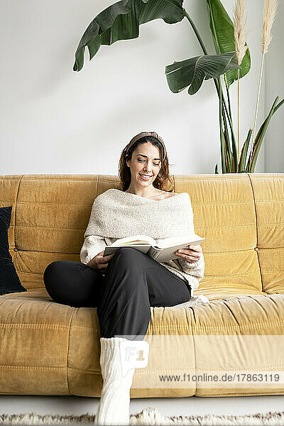 Beautiful girl on a sofa reading a book
