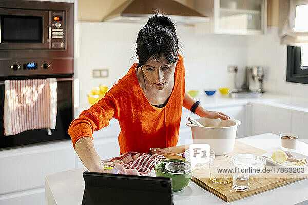 Woman Cooking cake and using the tablet at kitchen