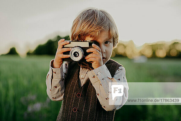 Hipster little boy with vintage camera outdoors. Child in costume