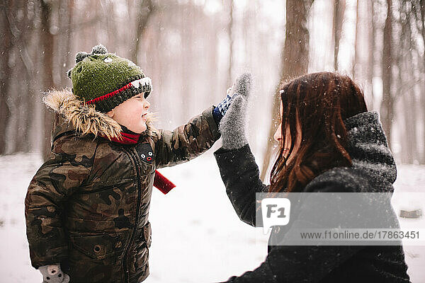 Mother and son giving high five in park during winter