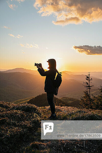 Silhouette of Man Holding Camera at Sunset on the Mountain