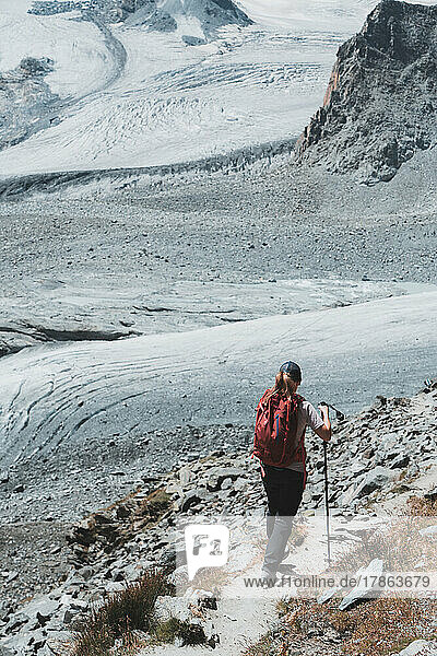 Female hiker walking on trail towards glaciers & crevasses