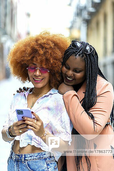 smiling friends looking with their smartphone