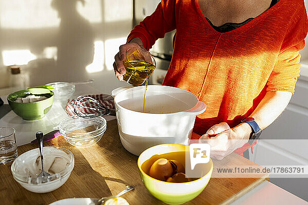 Woman pouring oil into a bowl in the kitchen.