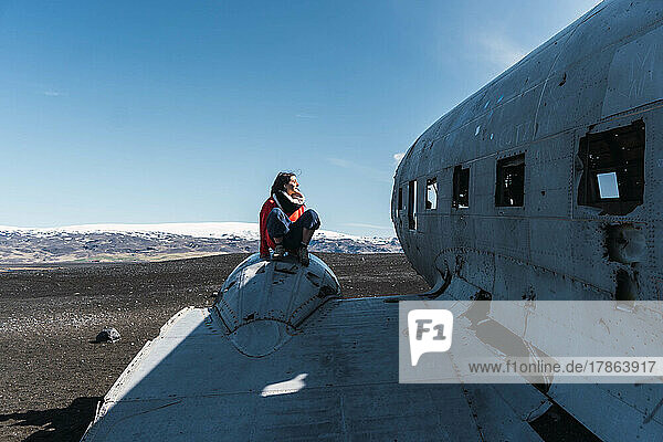 woman sitting on the wing of a lost plane
